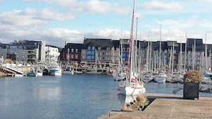 Ein Yachthafen mit mehreren Segelbooten, einer Uferpromenade und farbenfrohen Gebäuden im Hintergrund.