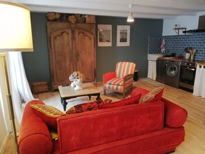 En hyggelig stue med en rød sofa, et træskab og et lille bord med en vase.