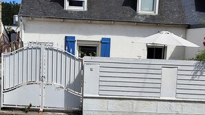 Ein zweistöckiges Haus mit weißer Fassade, einem roten Ziegeldach und einem weißen Tor.