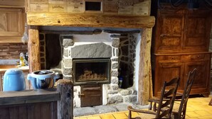 A rustic interior with a stone fireplace, wooden furniture, and a tiled floor. - 1802 Auvergne house (Saint-Donat)