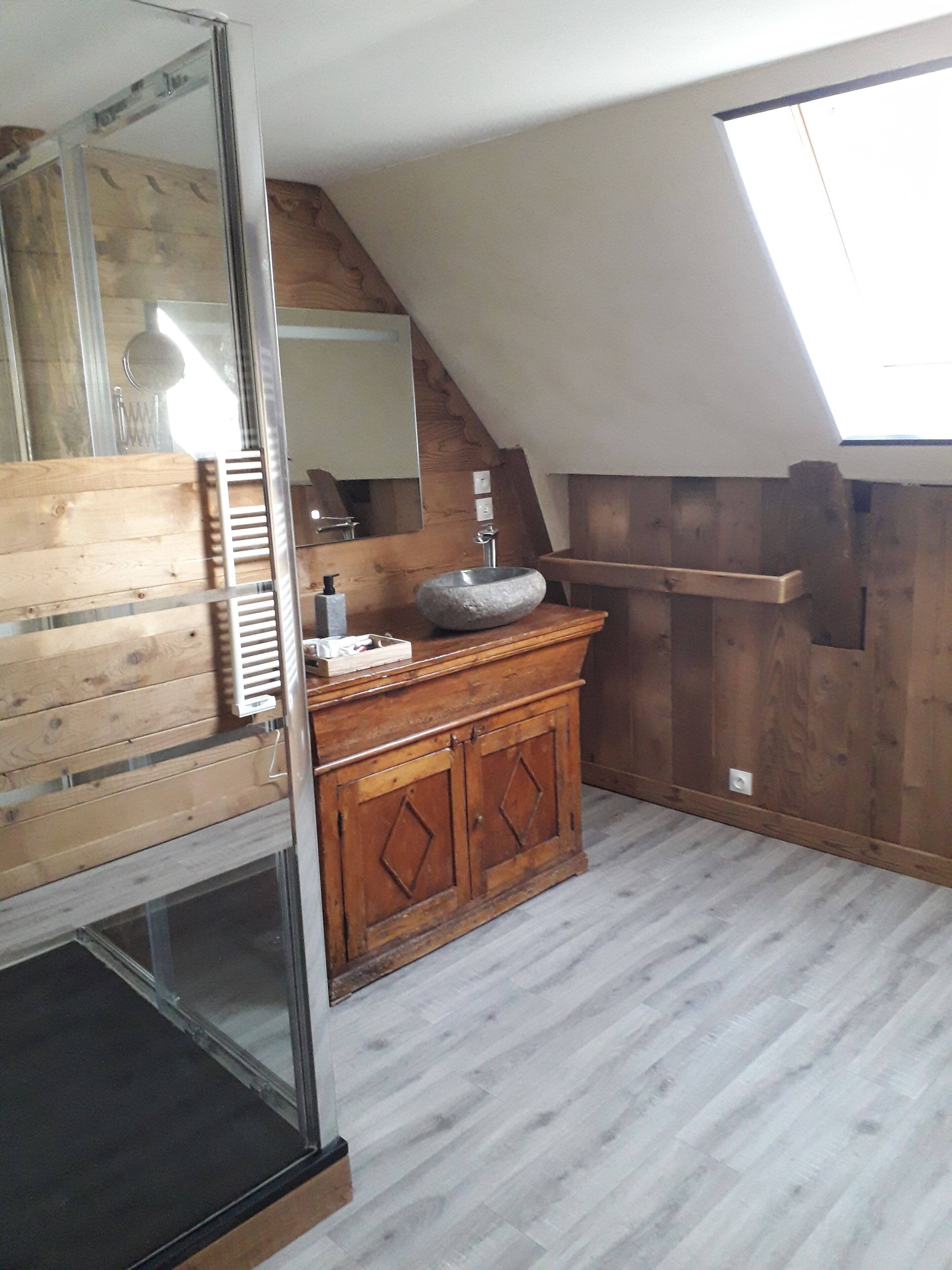 Une salle de bain avec un meuble-lavabo en bois, un évier en pierre et une lucarne.