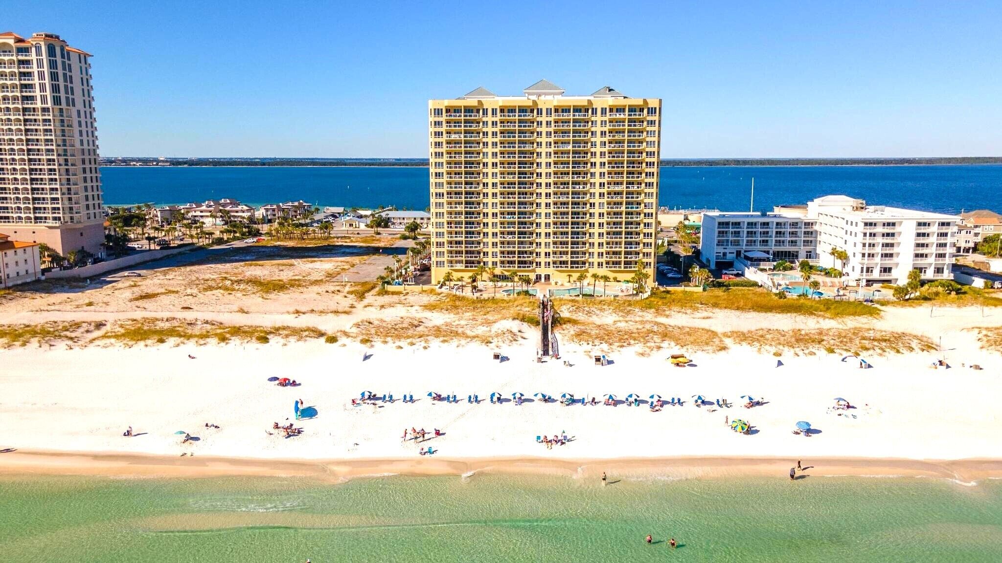 Hotel na praia com vários edifícios, areal arenoso e vista clara do oceano.