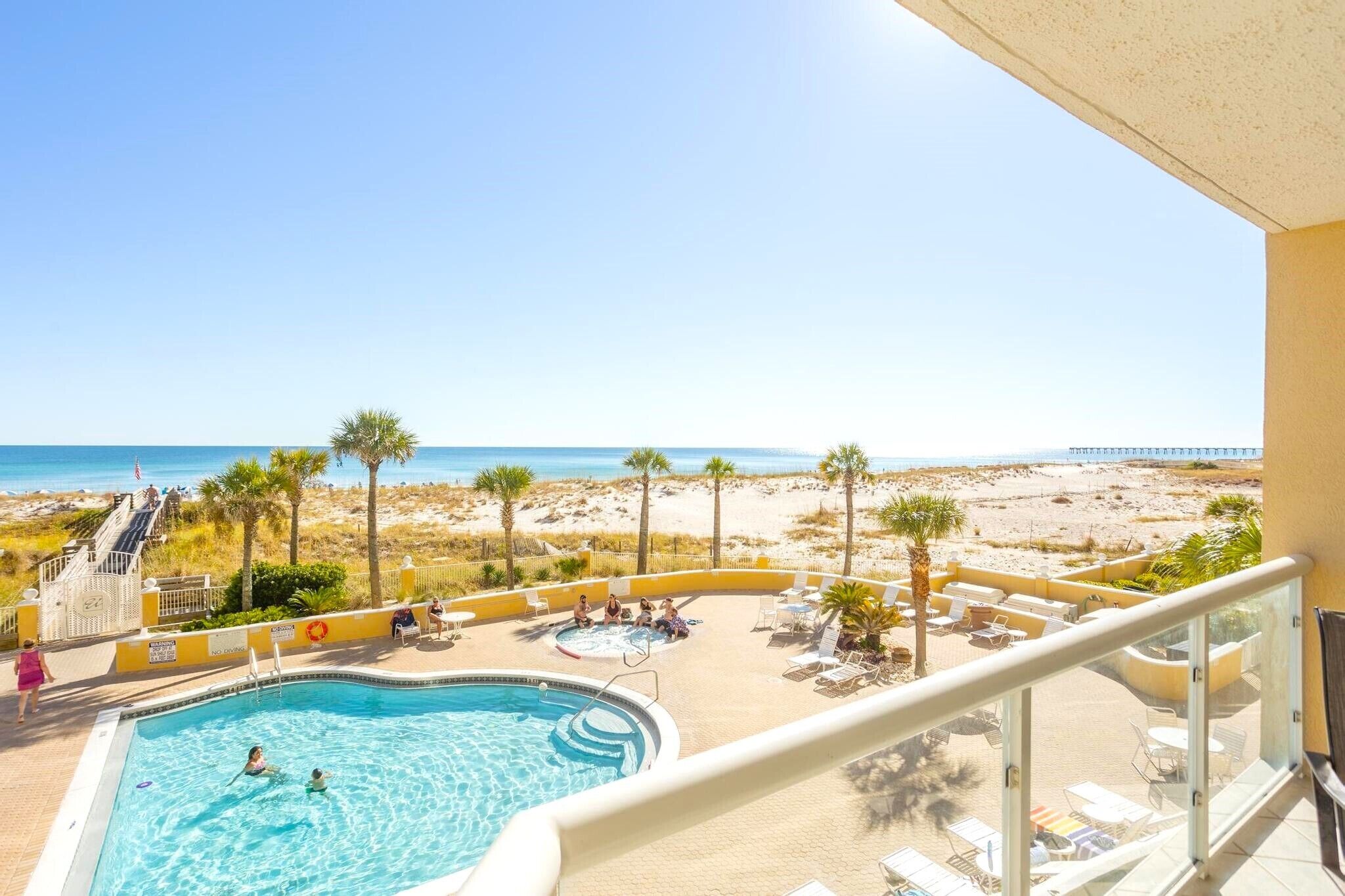 Ein Poolbereich mit Blick auf den Strand, Liegestühle und ein Rettungsschwimmerstand.