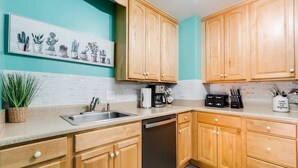 Una cocina con gabinetes de madera, lavavajillas, cafetera y un lavabo.