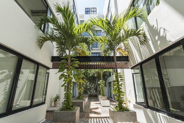 A modern building with large windows, a covered walkway, and potted plants.