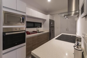 A modern kitchen with stainless steel appliances, a built-in oven, microwave, and a glass-fronted range hood.