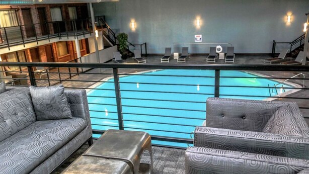 A pool area with lounge chairs and a sofa, a staircase, and a view of the building's interior. - CK Stay Hotel (Butte)
