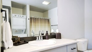 A bathroom with a white sink, a mirror, a towel rack, a shower curtain, and a toilet. - CK Stay Hotel (Butte)