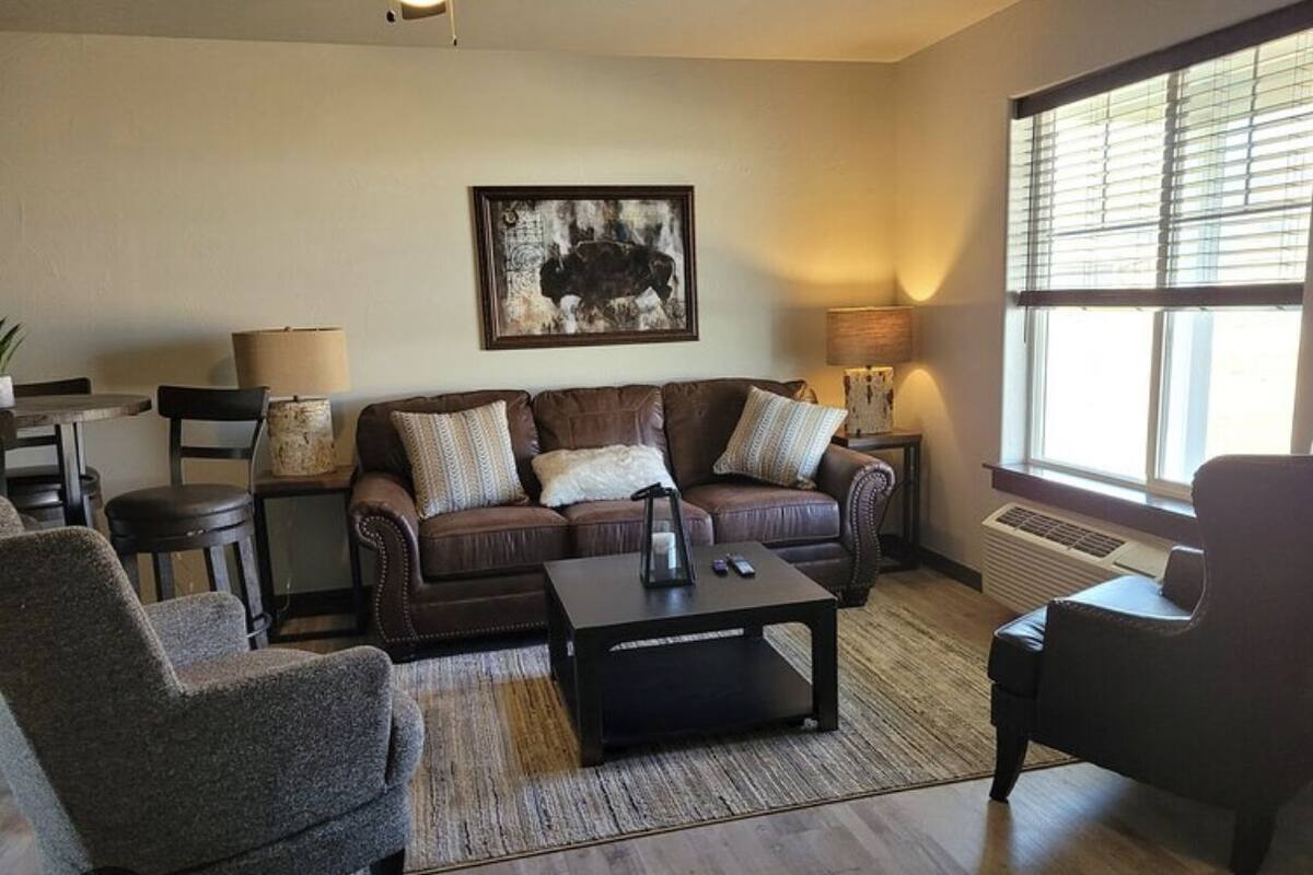 A living room with a brown leather sofa, two armchairs, a coffee table, and a lamp.