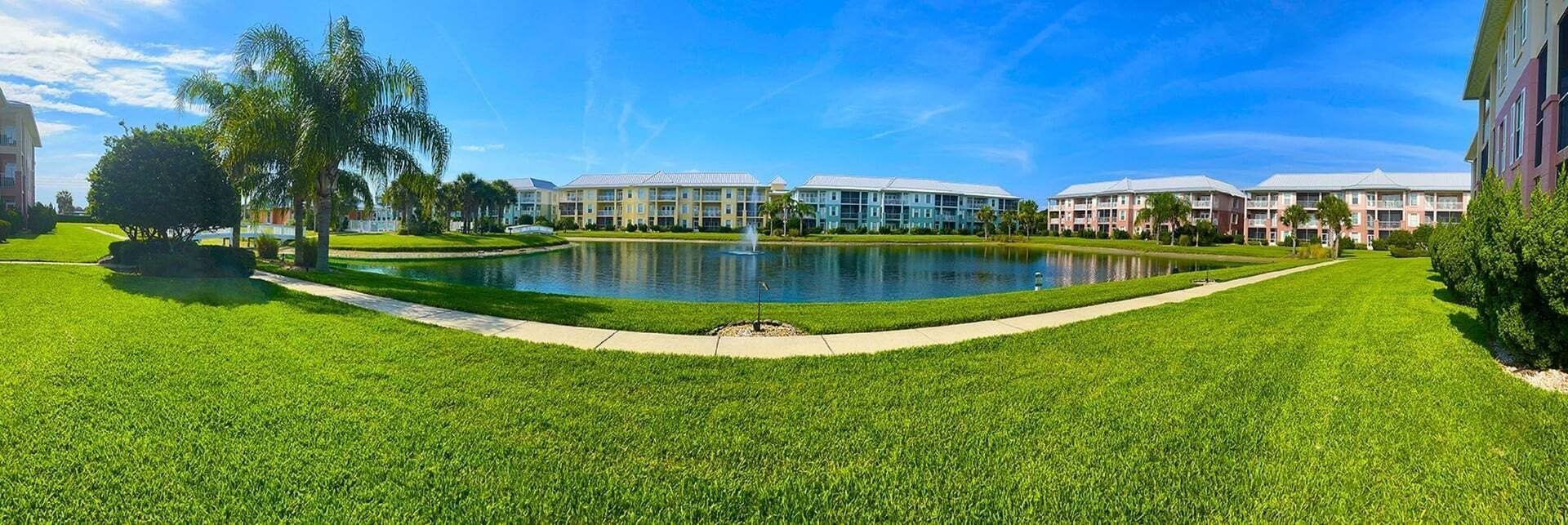 A well-maintained lawn with a central pond and a building complex in the background.