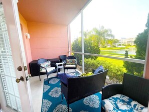 A balcony with wicker furniture and a view of a landscaped garden. - Seaside at Anastasia B102 (St. Augustine)