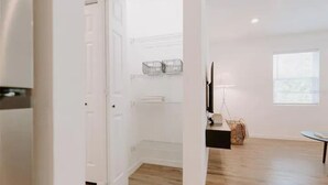 Une pièce spacieuse avec un plancher en bois, une porte blanche, une petite table et une fenêtre.