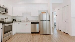 Une cuisine moderne avec des armoires blanches, des appareils en acier inoxydable et un plancher en bois.