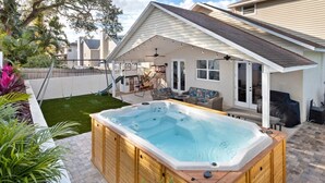 Ein Garten mit Whirlpool, Schaukel und überdachter Terrasse.