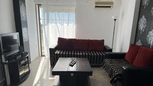 Ein modernes Wohnzimmer mit einer Couch, einem Couchtisch, einem Fernseher und einer Stehlampe.