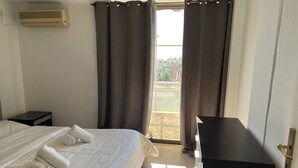 Ein Hotelzimmer mit Bett, Nachttisch, Schreibtisch und einem Fenster mit Vorhängen.
