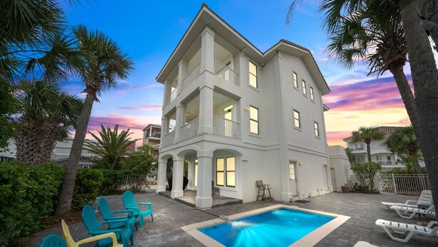 Une maison à deux étages avec une piscine, un espace salon extérieur et un balcon.