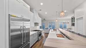 A modern kitchen with stainless steel appliances, a central island, and a dining area with a view.