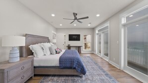 A bedroom with a bed, bedside table, lamp, and a ceiling fan.