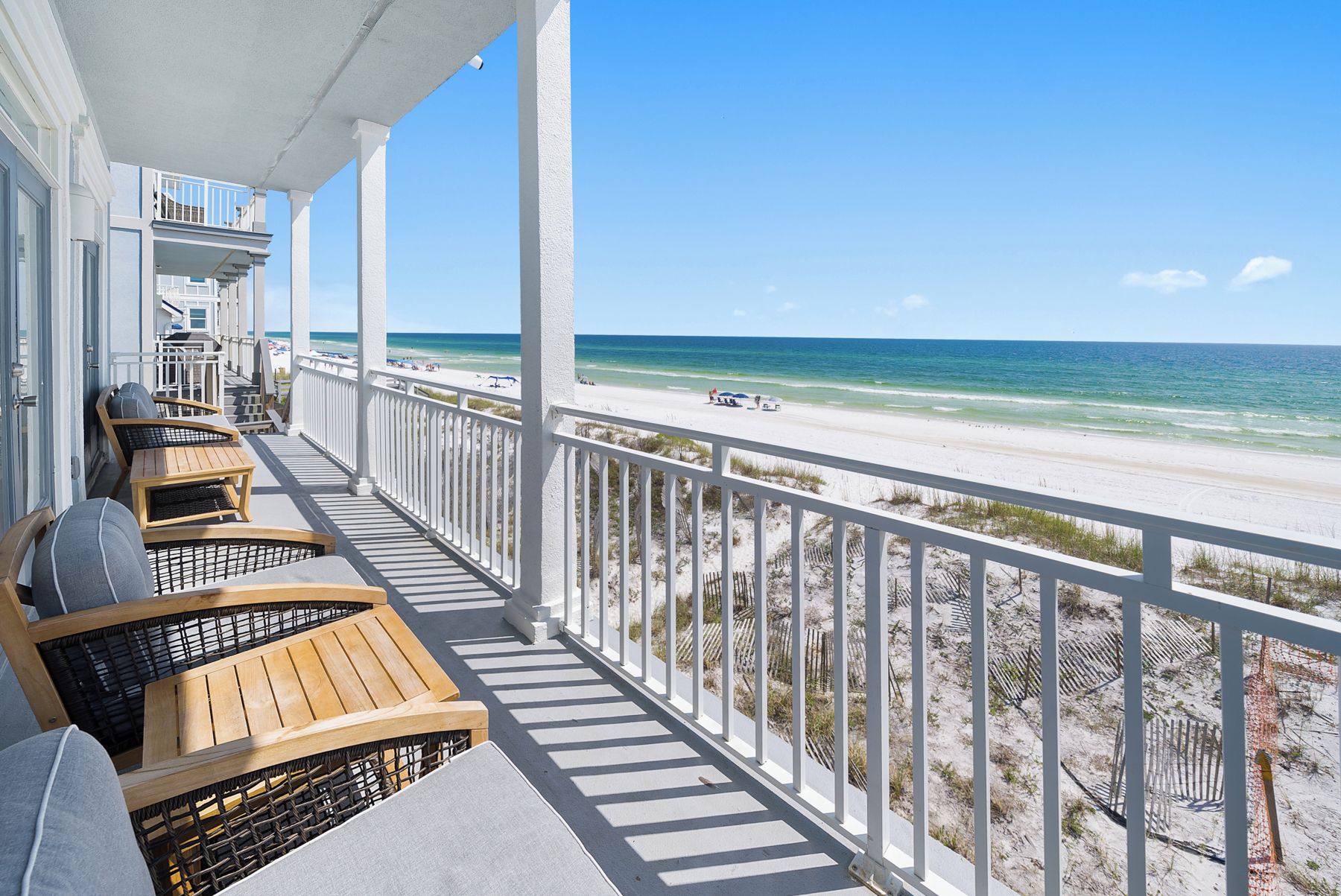 Ein Balkon mit Holzmöbeln mit Blick auf einen Strand.