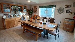Una cocina amplia con una isla grande, armarios de madera y un comedor con banco y sillas.