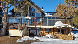Una casa moderna de varios pisos con amplios ventanales, un balcón y una zona de estar al aire libre techada.