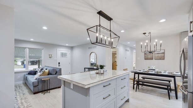 A modern kitchen with a central island, white cabinetry, and stainless steel appliances. - Charming 4BR near Convention Ctr., Main St, & LU -just 11 minutes to STL Airport (Saint Charles)