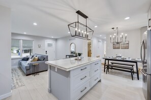 A modern kitchen with a central island, white cabinetry, and stainless steel appliances.