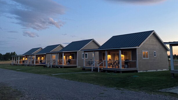 A row of single-story cabins with attached porches, each featuring a small deck and outdoor seating area.