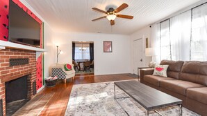 Una sala de estar con chimenea, ventilador de techo, sofá y mesa de centro.