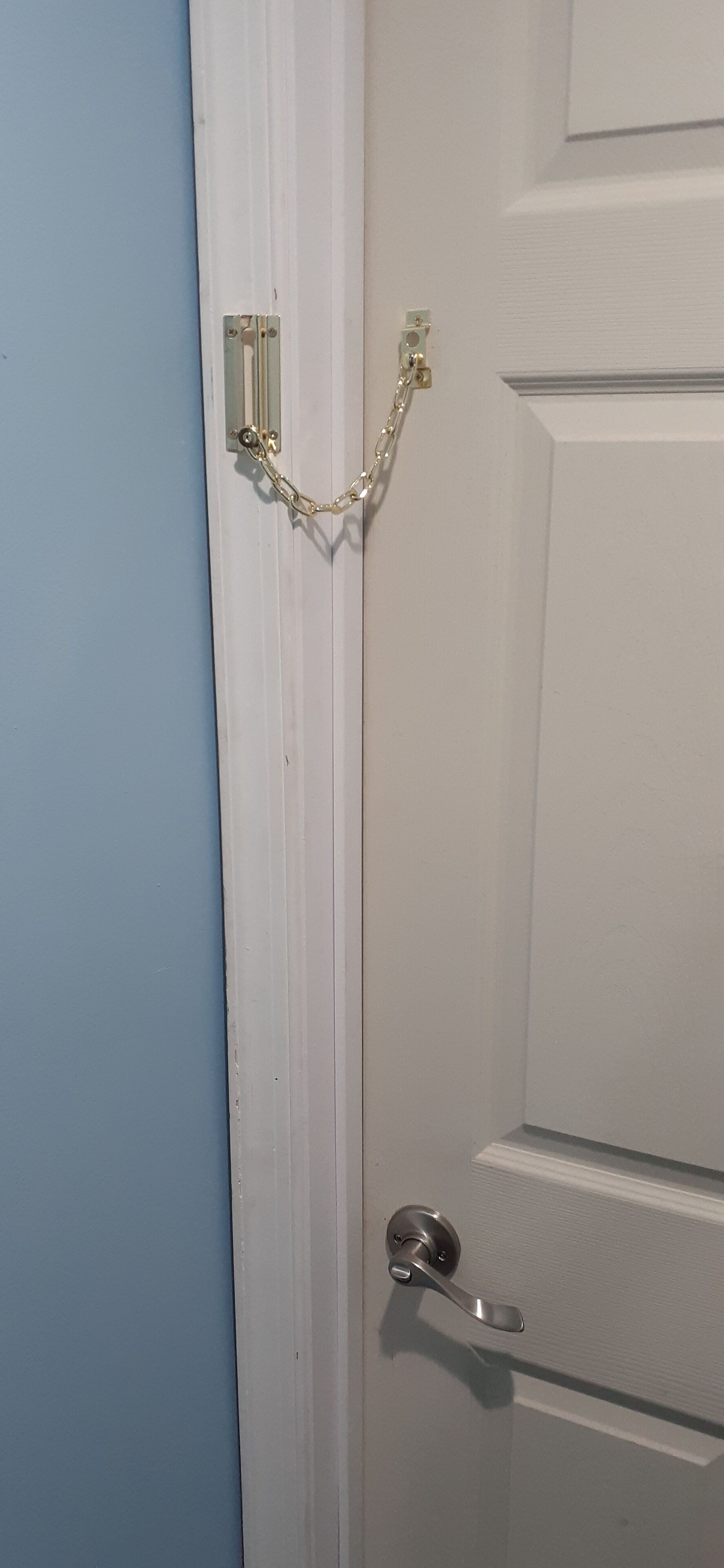 A white door with a silver handle and a chain lock.