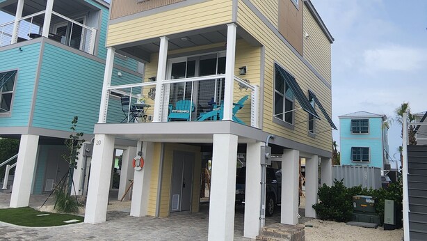 Un edificio residencial de varios pisos con balcón, entrada cubierta y acceso por coche.