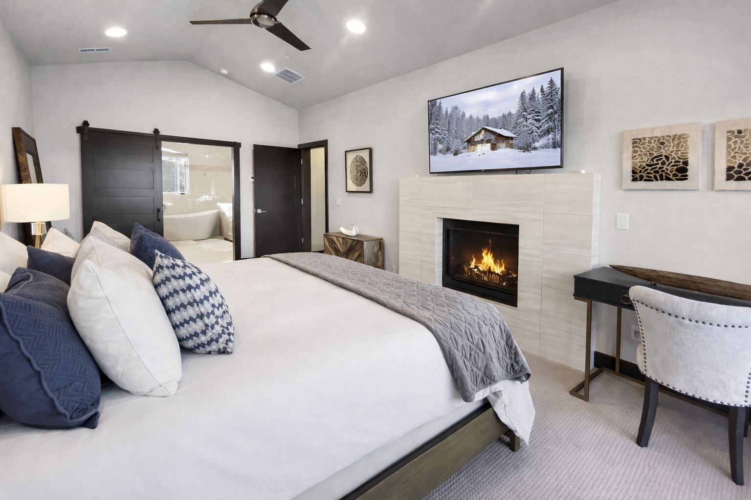 Ein Schlafzimmer mit Bett, Schreibtisch, Kamin und Fernseher an der Wand.