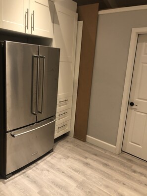 Compact kitchen with a stainless steel refrigerator and white cabinet.