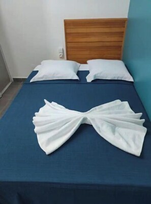 Restful retreat with a neatly made bed, featuring a wooden headboard and crisp white linens.