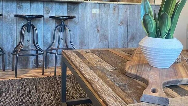 Une cuisine avec un îlot central en bois, des tabourets de bar, un réfrigérateur et une plante en pot.