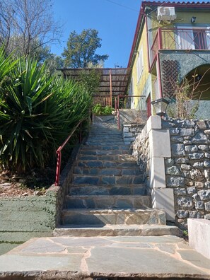 Escadaria de pedra que leva a um edifício com guarda-corrimão vermelho e parede de pedra.