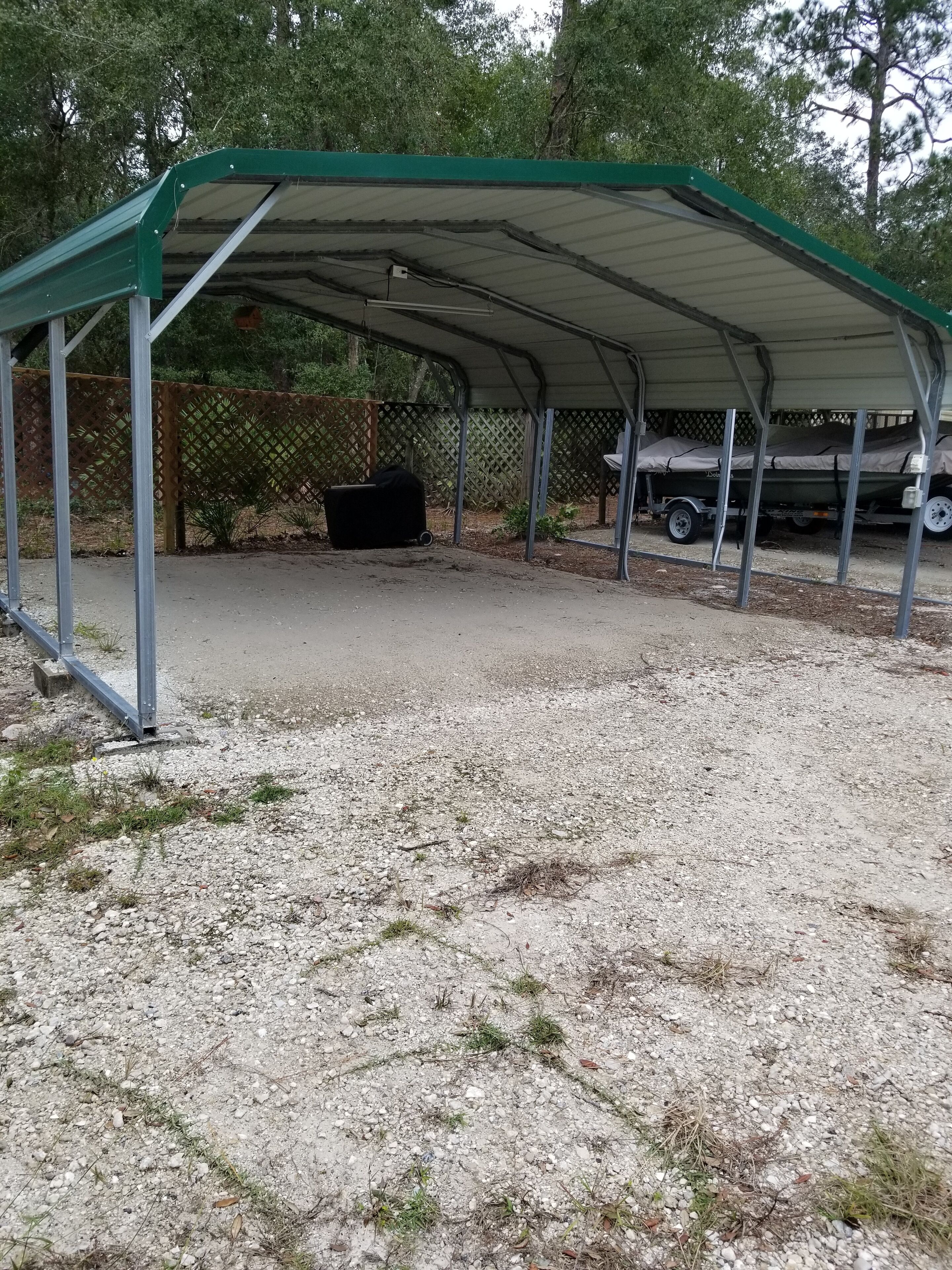 Un'area esterna riparata, con pavimento in ghiaia, recinzione in metallo e una struttura coperta.