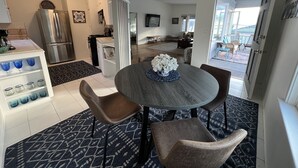 A modern kitchen with a stainless steel refrigerator, a dining area with a round table and chairs, and a view of the living room and outdoor space. - Ocean View 2 Bedroom 1 Bath Sunny clean Apartment (Laguna Beach)