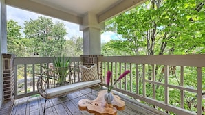 A wooden deck with a wicker sofa and a wooden table with a vase. - Stylish Uptown condo in Historic 4th Ward! (Charlotte)
