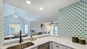 A modern kitchen with a large island, a built-in dishwasher, and a ceiling fan. - Stylish Uptown condo in Historic 4th Ward! (Charlotte)