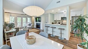 A spacious kitchen with white cabinets, a central island with bar stools, and a large pendant light. - Stylish Uptown condo in Historic 4th Ward! (Charlotte)
