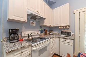 A kitchen with white cabinets, a stove, a microwave, and a coffee maker. - Artist House Lower in Forsyth Park Neighborhood Hist Savannah (Savannah)