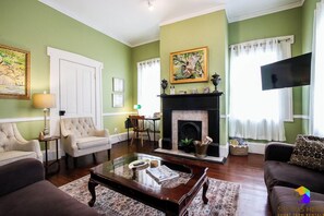 Sala de estar com lareira, paredes verdes e televisão.
