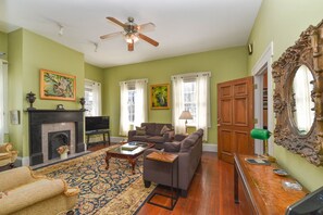 A living room with a fireplace, sofa, and television. - Artist House Lower in Forsyth Park Neighborhood Hist Savannah (Savannah)