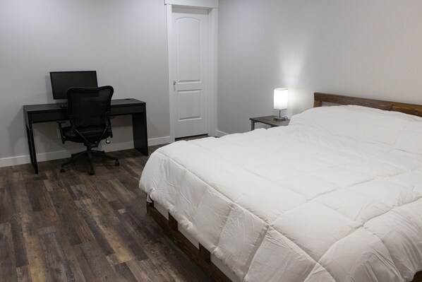 Une chambre à coucher avec un lit, un bureau avec un ordinateur et une porte.