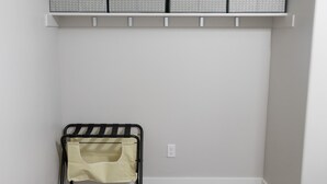 A corner room with a wooden floor, a black metal rack with a beige bag, and a grey patterned shelf above. - New home sleeps 10, open floor plan & amazing view (Manila)