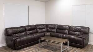 A sectional sofa with a metal frame and a wooden coffee table in a room with wooden flooring and white walls. - New home sleeps 10, open floor plan & amazing view (Manila)