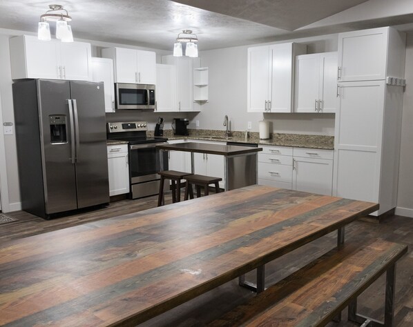 A modern kitchen with white cabinets, stainless steel appliances, a wooden bench, and pendant lighting. - New home sleeps 10, open floor plan & amazing view (Manila)
