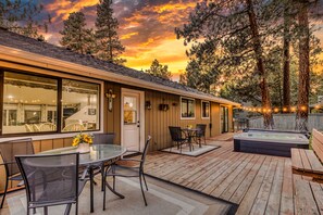 A wooden deck with outdoor seating, a hot tub, and a view of the surrounding forest. - House + Bonus Room, HOT TUB, Huge Yard, Dogs OK (Sisters)